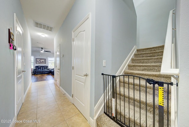 hallway featuring stairs, visible vents, baseboards, and light tile patterned flooring