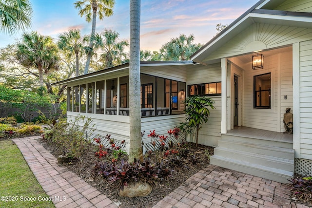 property exterior at dusk featuring a sunroom