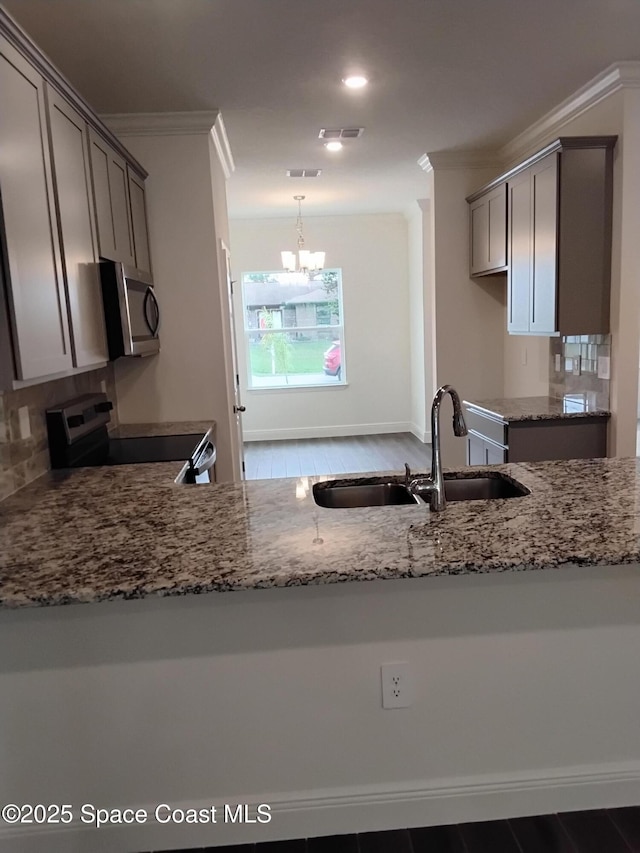 kitchen with sink, appliances with stainless steel finishes, tasteful backsplash, ornamental molding, and light stone countertops