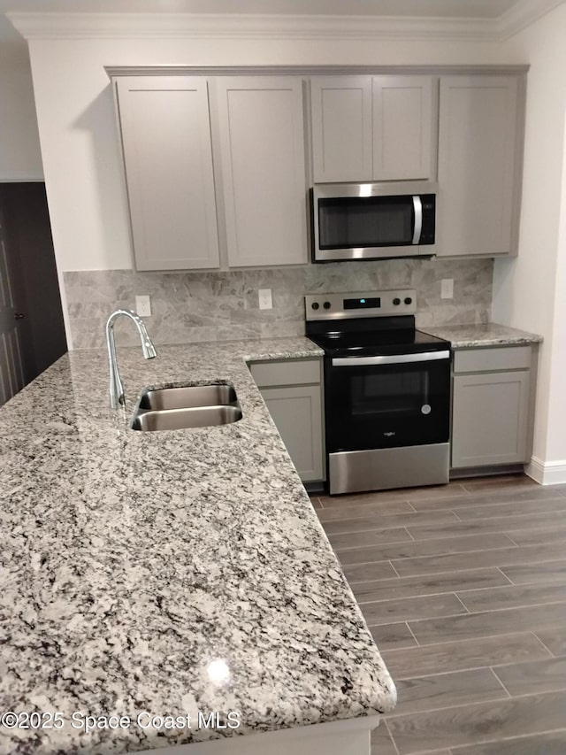 kitchen with sink, crown molding, appliances with stainless steel finishes, gray cabinets, and backsplash