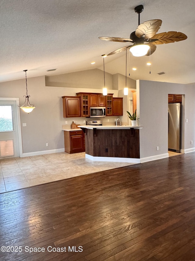 kitchen featuring ceiling fan, appliances with stainless steel finishes, decorative light fixtures, and light hardwood / wood-style flooring