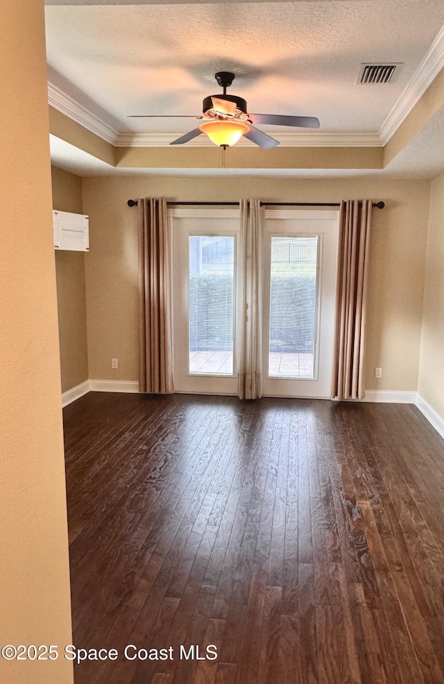 unfurnished room featuring a raised ceiling, crown molding, a textured ceiling, and dark hardwood / wood-style flooring