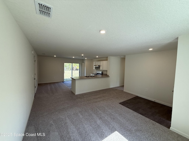 unfurnished living room with sink, dark carpet, and a textured ceiling