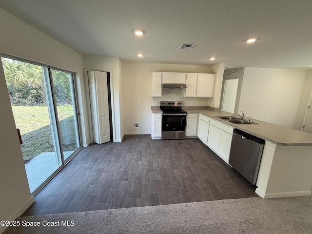 kitchen featuring sink, dark wood-type flooring, appliances with stainless steel finishes, white cabinetry, and kitchen peninsula