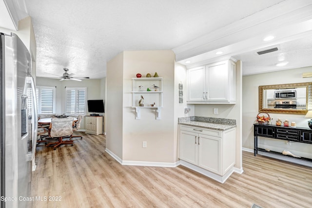 kitchen with appliances with stainless steel finishes, light hardwood / wood-style floors, a textured ceiling, and white cabinets