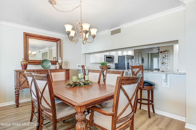 dining area featuring a notable chandelier, crown molding, light hardwood / wood-style floors, and a textured ceiling