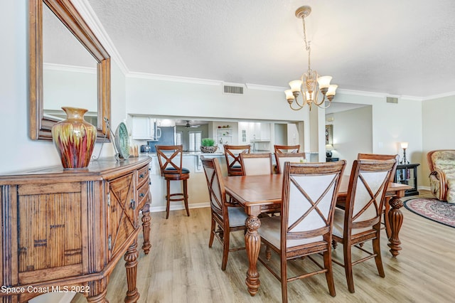 dining space featuring ornamental molding, a textured ceiling, light hardwood / wood-style flooring, and a notable chandelier