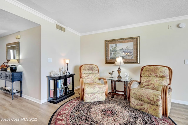 sitting room featuring crown molding, a textured ceiling, and light hardwood / wood-style flooring