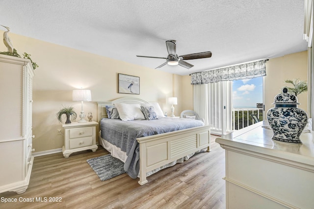 bedroom with ceiling fan, access to exterior, a textured ceiling, and light hardwood / wood-style flooring