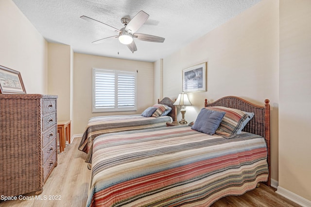 bedroom featuring ceiling fan, light hardwood / wood-style flooring, and a textured ceiling