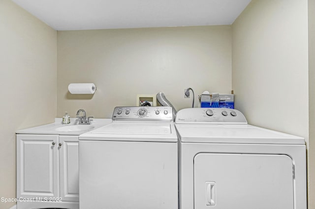 washroom featuring sink, washer and clothes dryer, and cabinets