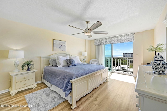 bedroom with ceiling fan, access to exterior, light hardwood / wood-style flooring, and a textured ceiling