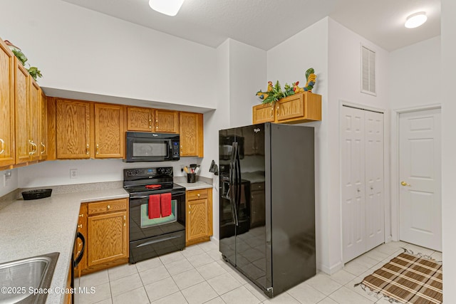 kitchen featuring sink, light tile patterned floors, a high ceiling, and black appliances