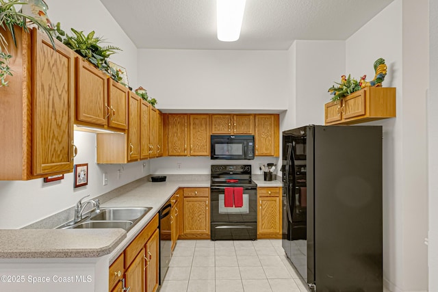 kitchen with light tile patterned floors, sink, a textured ceiling, and black appliances