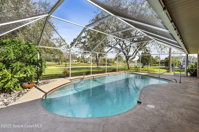 view of pool with glass enclosure, a patio, and a lawn