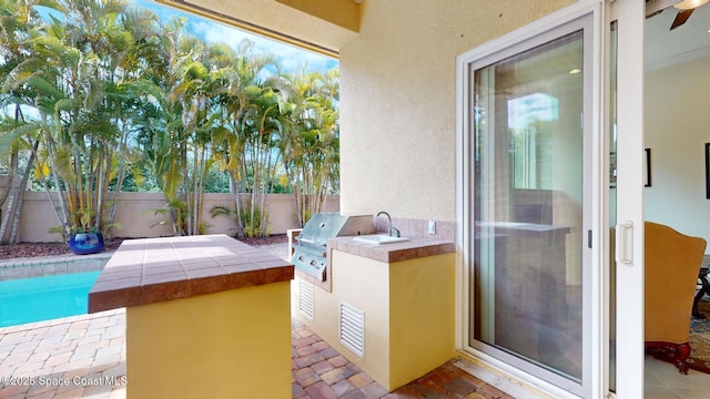 view of patio featuring a fenced in pool, grilling area, and an outdoor kitchen