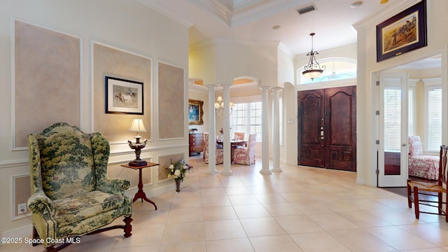 entrance foyer featuring ornate columns, ornamental molding, a towering ceiling, and light tile patterned floors