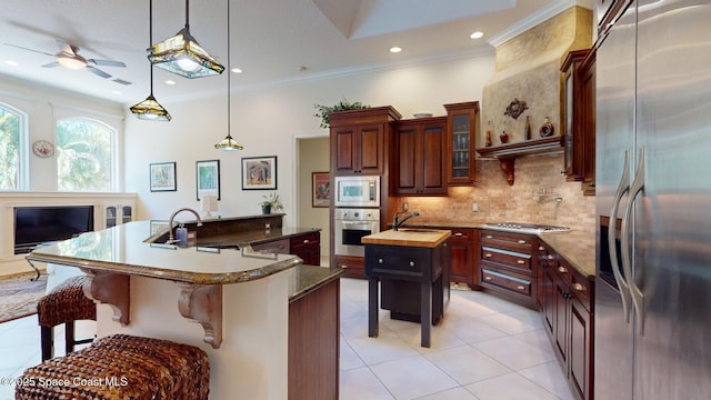 kitchen with sink, backsplash, stainless steel appliances, ornamental molding, and an island with sink