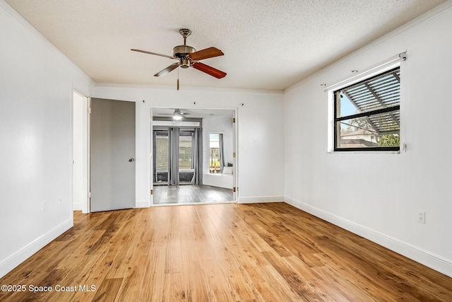 spare room with ornamental molding, a wealth of natural light, light hardwood / wood-style floors, and a textured ceiling