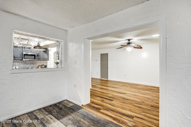 unfurnished room featuring hardwood / wood-style flooring, ceiling fan, and a textured ceiling