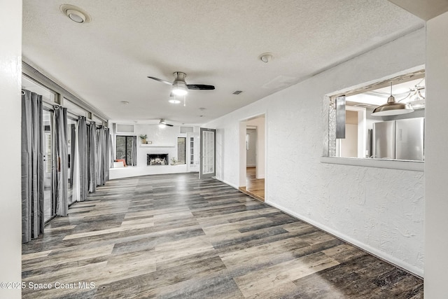 unfurnished living room with hardwood / wood-style floors, a textured ceiling, and ceiling fan