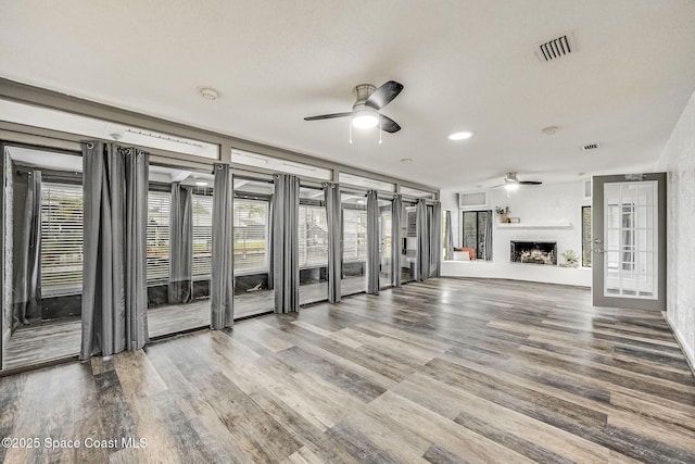 unfurnished living room featuring ceiling fan, hardwood / wood-style floors, and a textured ceiling