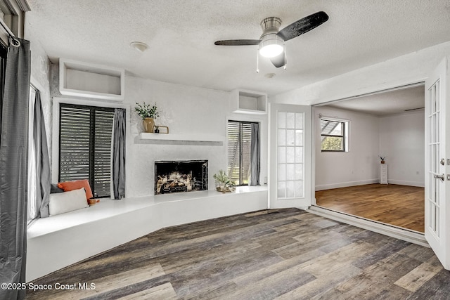 unfurnished living room featuring wood-type flooring, ceiling fan, a textured ceiling, and french doors