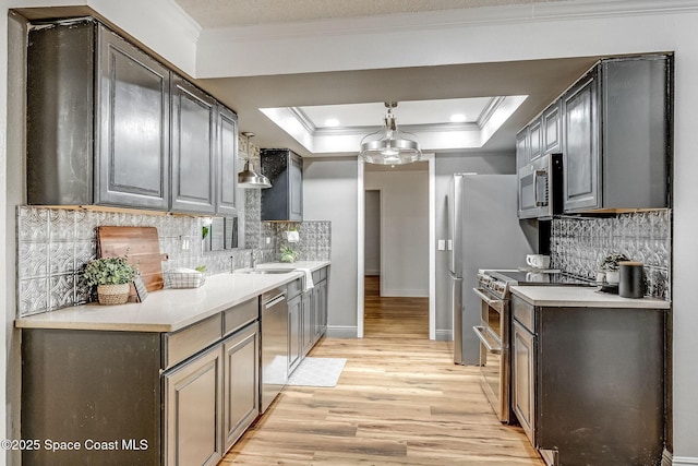 kitchen with a raised ceiling, appliances with stainless steel finishes, and backsplash