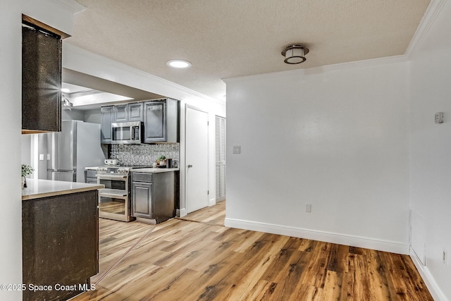 kitchen featuring crown molding, stainless steel appliances, light hardwood / wood-style floors, and decorative backsplash