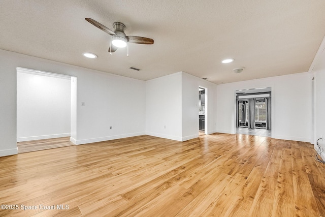 unfurnished living room with ceiling fan, light hardwood / wood-style floors, and a textured ceiling