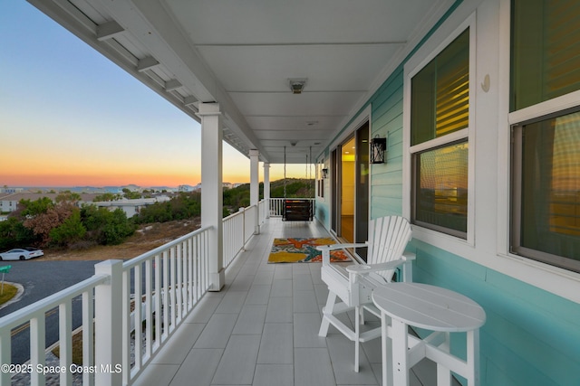 balcony at dusk featuring a porch