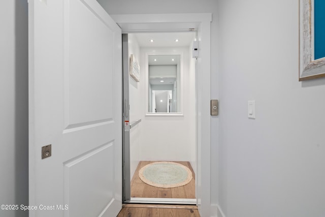 hallway with wood-type flooring and elevator