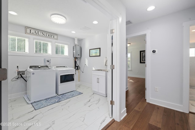 clothes washing area with water heater, washer and dryer, and sink