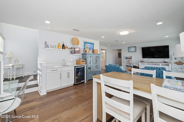 dining space featuring wet bar, beverage cooler, and dark hardwood / wood-style flooring