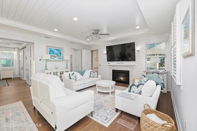 living room featuring dark hardwood / wood-style flooring, crown molding, a raised ceiling, and ceiling fan