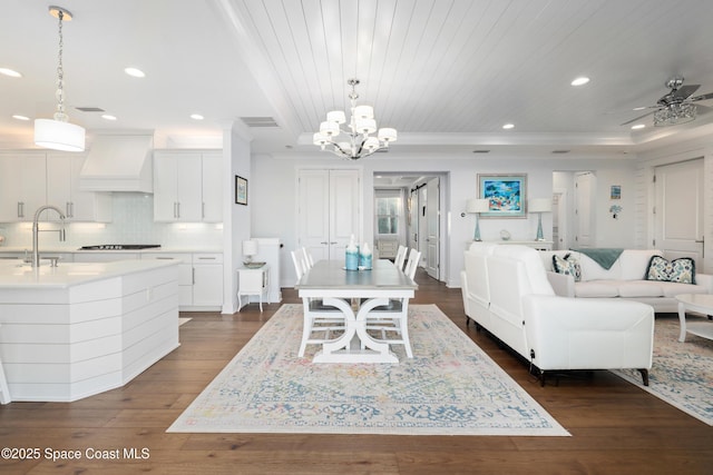 dining space featuring sink, dark wood-type flooring, ceiling fan, a tray ceiling, and wooden ceiling