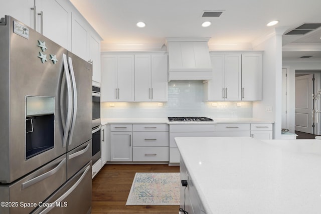 kitchen with white cabinetry, backsplash, stainless steel appliances, dark hardwood / wood-style floors, and custom exhaust hood