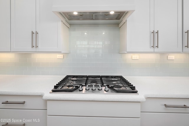 details with white cabinetry, decorative backsplash, custom range hood, and stainless steel gas stovetop