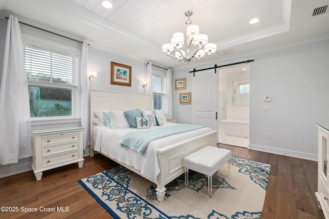 bedroom with dark wood-type flooring, a tray ceiling, a barn door, and multiple windows