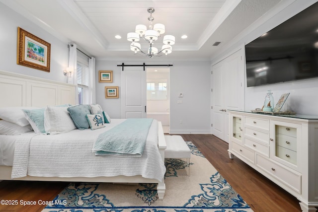 bedroom with a raised ceiling, a barn door, dark hardwood / wood-style floors, and multiple windows