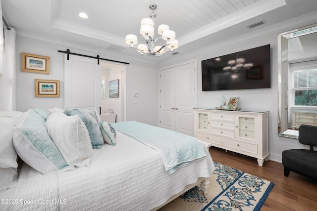 bedroom with crown molding, dark hardwood / wood-style flooring, a barn door, and a raised ceiling