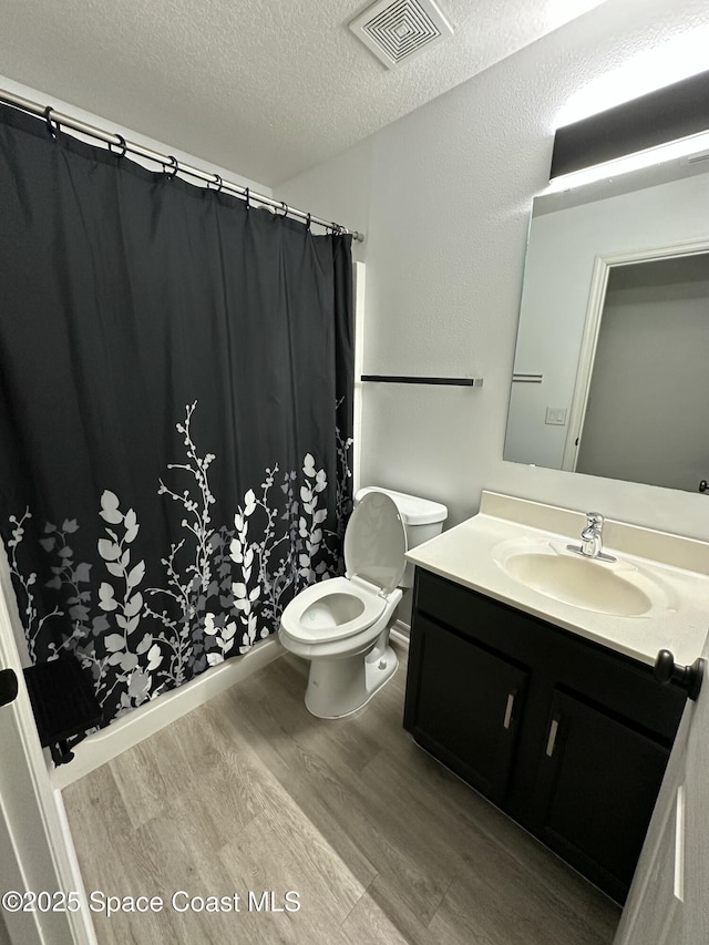 bathroom with wood-type flooring, toilet, a textured ceiling, and vanity