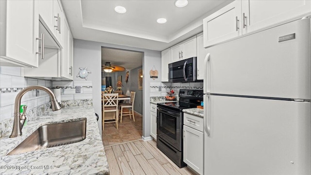 kitchen with white cabinets, white fridge, sink, and electric range