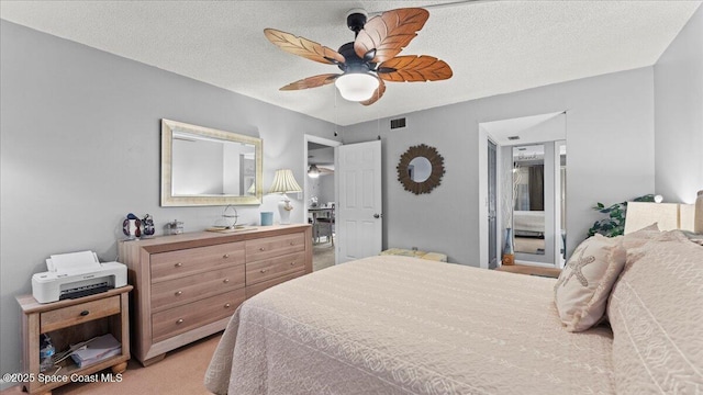 carpeted bedroom with ceiling fan and a textured ceiling