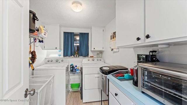 laundry area featuring separate washer and dryer, a textured ceiling, and light wood-type flooring