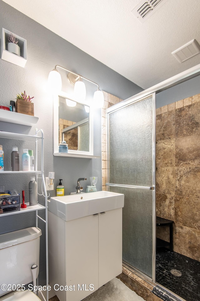 bathroom with toilet, a shower with door, and vanity