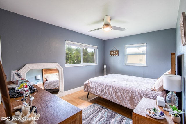 bedroom featuring ceiling fan, wood-type flooring, and multiple windows