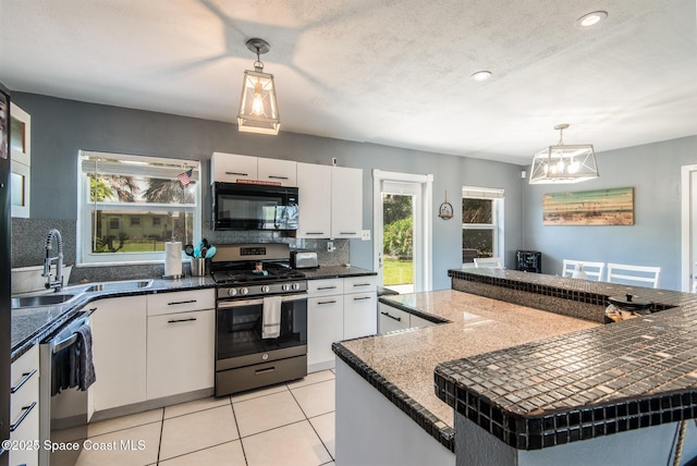 kitchen with stainless steel appliances, white cabinetry, and decorative light fixtures