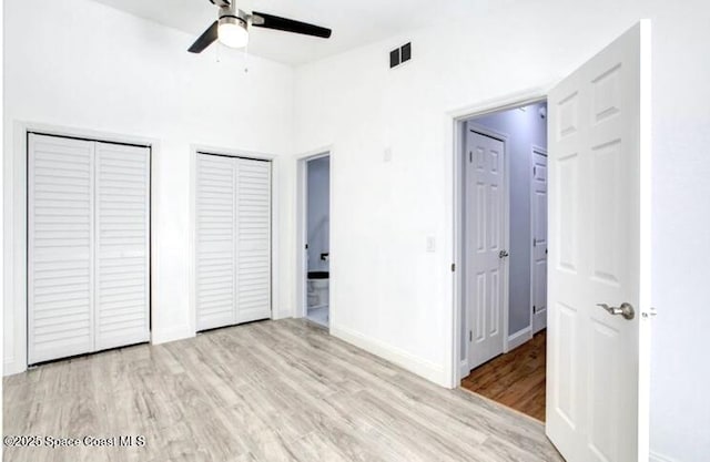 unfurnished bedroom featuring ceiling fan, two closets, and light wood-type flooring