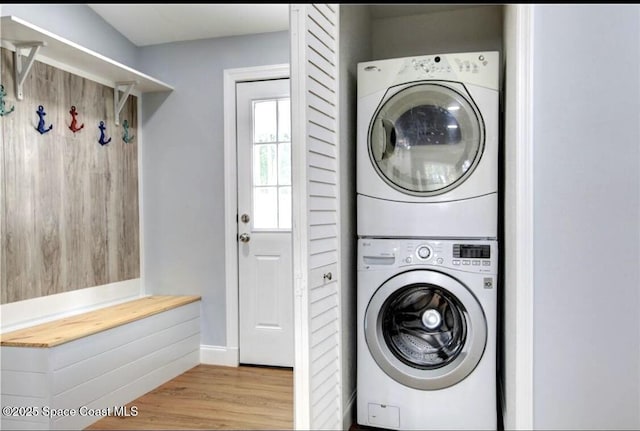 laundry room with stacked washer / drying machine and light hardwood / wood-style flooring